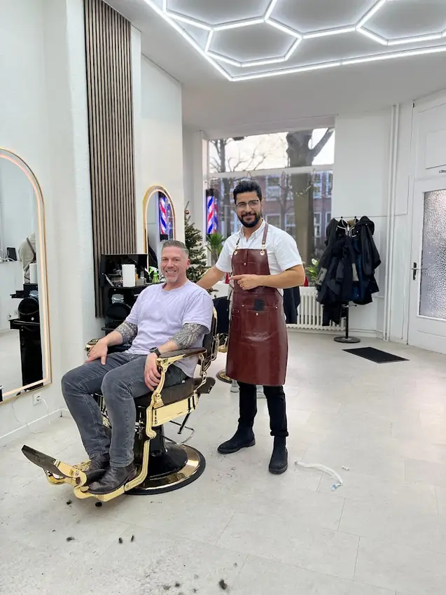 Barber mit zufriedenem Kunden im goldenen Barber-Stuhl bei Bro's Barber Kiel